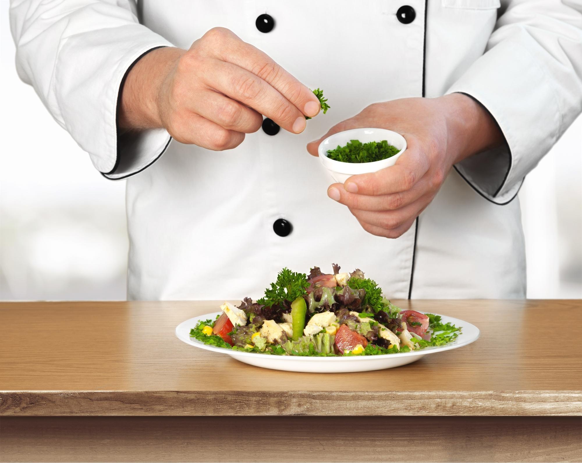 Chef arranging plated seasonal salad on wooden table